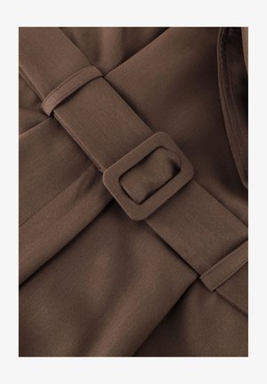 Brown fabric belt with matching rectangular buckle on textured brown garment, showing seam details and stitching.