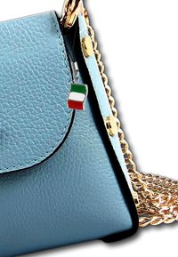 Lichtblauwe leren handtas met gouden kettingstrap. Voorzien van een klep sluiting en een klein Italiaans vlaggetje charm dat aan de rits is bevestigd.