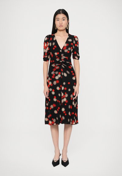 Schwarzes Kleid mit roten und beigen Punkten, V-Ausschnitt, kurzen Puffärmeln, tailliert und knielang. Glatter Stoff mit fließender Silhouette.