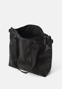 Svart tote bag laget av teksturert stoff, med doble solide håndtak og åpen toppdesign for enkel tilgang til innsiden.