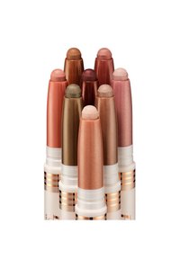 Eight tinted lip balms in various shades of bronze, peach, and rose, with a glossy finish, cylindrical design, and rounded tips.