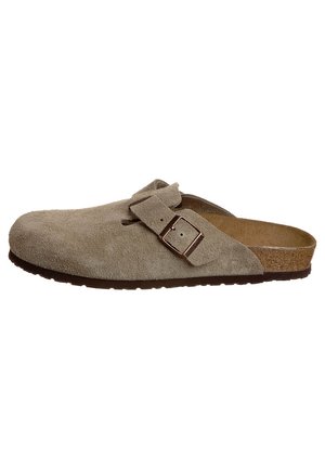 Scarpa slip-on in suede beige con una fascia ampia e una fibbia in metallo. Punta arrotondata e soletta testurizzata. Suola in gomma per una buona aderenza. Profilo piatto.