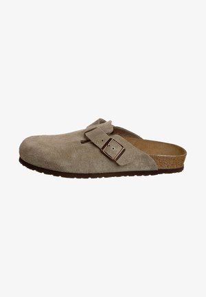 Scarpa slip-on in suede beige con una fascia ampia e una fibbia in metallo. Punta arrotondata e soletta testurizzata. Suola in gomma per una buona aderenza. Profilo piatto.