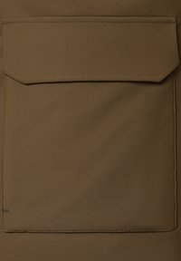 Brązowa tkanina o gładkiej fakturze, z dużą, płaską kieszenią na środku, wykończoną szwem wzdłuż krawędzi.