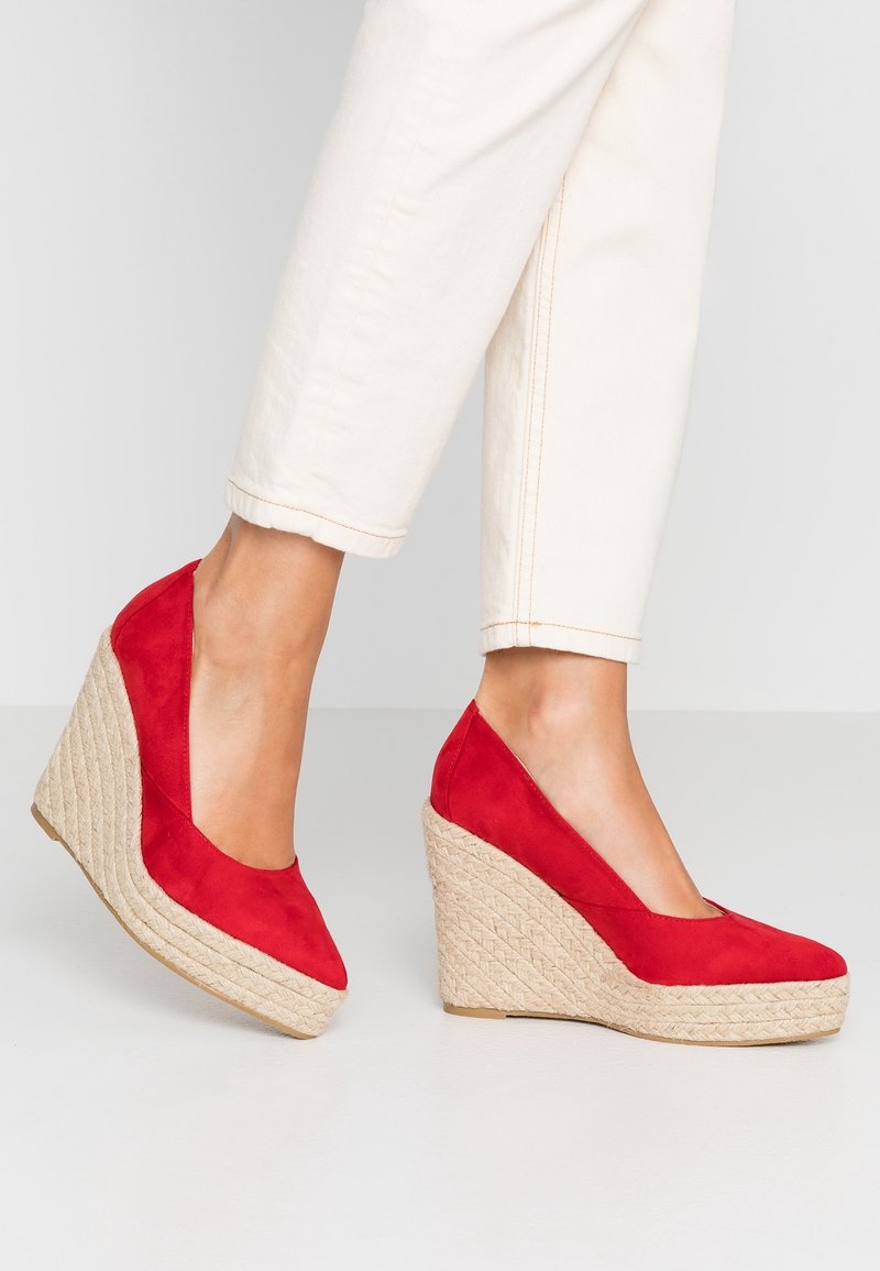 Escarpins compensés en daim rouge avec une semelle en jute texturée rappelant une corde. Le design présente un bout arrondi et une finition lisse sur la tige.