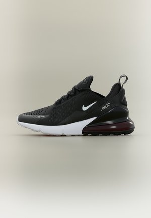 Μαύρο και άσπρο sneaker Nike Air Max 270 με διχτυωτό επάνω μέρος, ορατή μονάδα αέρα στη φτέρνα και θηλιά στο πίσω μέρος.