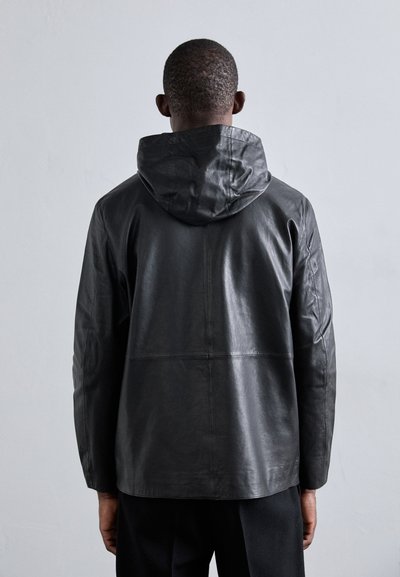 Jaqueta de couro preto com capuz, apresentando um corte descontraído, textura suave e costuras visíveis nas costas.