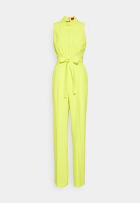 Combinaison jaune fluo sans manches avec col montant, taille cintrée, ceinture à nouer et pantalon droit sur fond blanc.