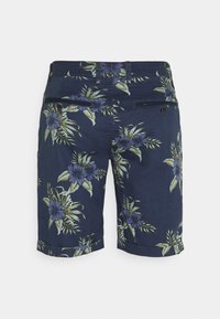 Tummansinisiä shortseja, joissa on kukkakuosi vihreillä lehdillä ja violetilla kukilla. Sisältää kaksi takataskua, joissa on tummat napit.