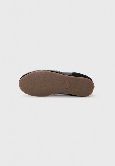 Black shoe sole with a smooth texture and rubber material. Features a slightly raised heel and a circular logo imprint in the center.