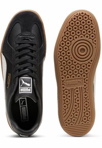 Czarne skórzane i zamszowe sneakersy z białymi akcentami, teksturowana gumowa podeszwa, okrągłe wzory i złote logo na języku.