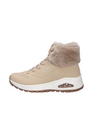 Baskets montantes beiges avec un col en fourrure tan pelucheux, texture perforée sur le dessus, semelle intermédiaire blanche et coussin d'air visible au niveau du talon.