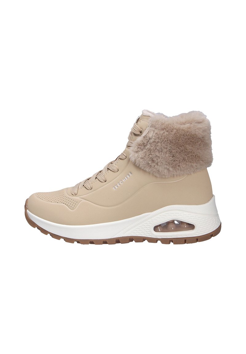 Zapatilla alta beige con un suave cuello de piel de tono marrón claro, textura perforada en la parte superior, media suela blanca y un cojín de aire visible en el talón.