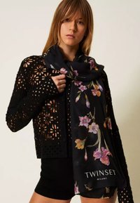 Cardigan nero all'uncinetto con sciarpa nera a motivo floreale, caratterizzata da fiori pastello e logo. Il design è leggero con una lavorazione aperta.