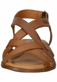 Brown leather sandal with crisscross straps, open toe design, flat sole, and a buckle for adjustment. Smooth texture and minimal detailing.