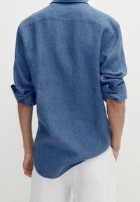 Slim-Fit, Langarmhemd aus mittlerem blauen Denim. Weicher Stoff, einzelne Tasche, aufgerollte Ärmel, abgerundeter Saum, Rückenpasse mit Nahtdetails.