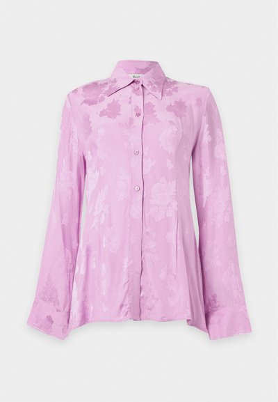 Blouse rose à manches longues avec boutons, motif floral subtil et col pointu, présentée sur un fond clair uni.