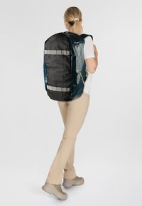 Zaino nero e turchese con strisce riflettenti, realizzato in materiale resistente, caratterizzato da un design spazioso, spallacci larghi e una finitura testurizzata.