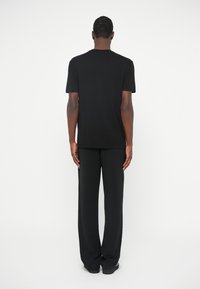 T-shirt preta de mangas curtas e gola redonda, emparelhada com calças largas pretas. Tecido suave, design simples e cores neutras.