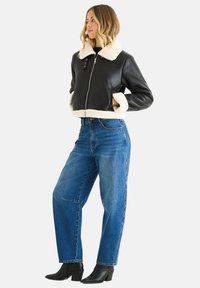 Black leather cropped jacket with a cream faux shearling collar and cuffs, paired with high-waisted blue jeans and black ankle boots.