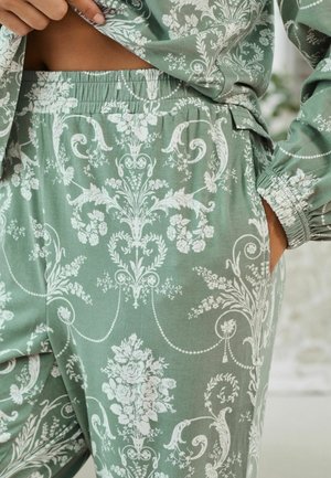Set di loungewear verde in tessuto con intricate fantasie floreali bianche, vita elasticizzata e tasche laterali per praticità e comfort.