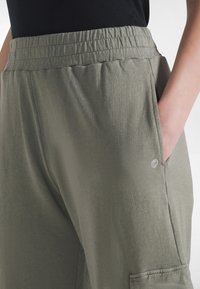 Spodnie o luźnym kroju w kolorze khaki z elastycznym pasem, bocznymi kieszeniami i subtelnym logo na nogawce. Wykonane z miękkiej, lekkiej dzianiny jersey.