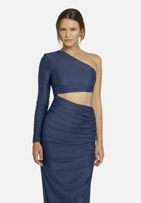 Asymmetrische marineblauwe jurk met één lange mouw. Kenmerkt zich door gerimpelde details en een uitsparing, gemaakt van een gladde, rekbare stof.