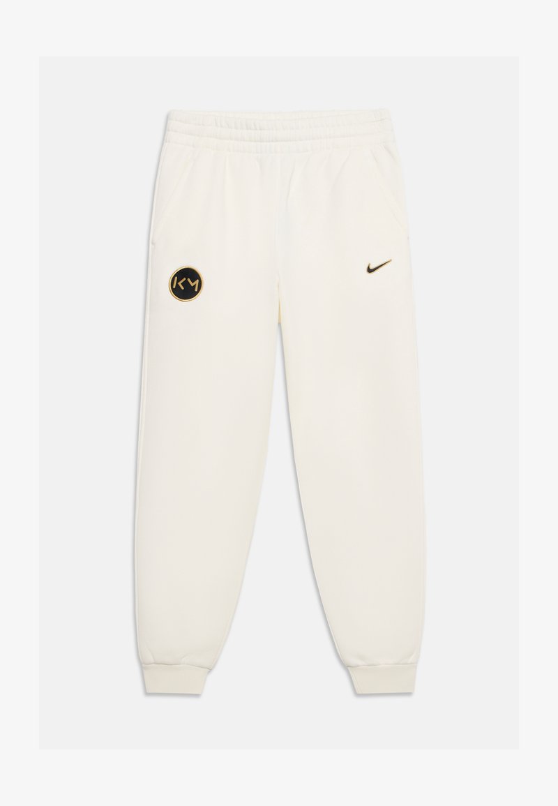 Λευκή φόρμα Nike με ελαστική μέση και μανσέτες, με μαύρο και χρυσό λογότυπο KM στον αριστερό μηρό και μικρό μαύρο σήμα Nike στον δεξί μηρό.