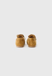 Suede mokkasiner i lys brun med en glatt overflate, rund tå, snøredetaljer og en minimalistisk gummisåle.