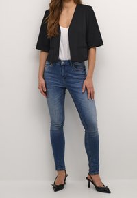 Svart kort blazer med korta ärmar, kombinerad med ljusblå skinny jeans. Svarta spetsiga klackskor fulländar outfiten.