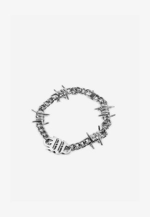 Sudraba ķēdes aproce ar dzeloņstieņa stila saitēm un aizdari, attēlota uz balta fona.