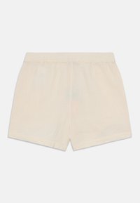 Ljusbeige bomullsbyxor med elastisk midja, har en avslappnad passform och mjuk textur. Inga synliga fickor eller mönster.