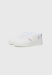 Hvit sneakers med lyse lilla detaljer, glatt lærmateriale, flate lisser og teksturert gummisåle. Lacoste-logo på siden.