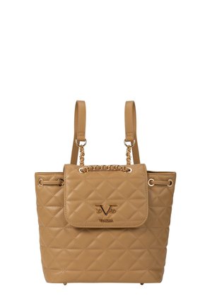 Tan gewatteerde leren handtas met gouden kettingdetail, dubbele schouderbanden en een voorflap met een metalen logo-embleem.