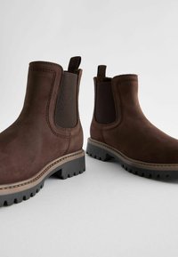 Bottines en cuir marron avec des panneaux latéraux élastiques, une surface texturée et des semelles en caoutchouc durables avec des patins profonds pour une bonne adhérence.