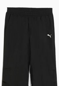 Sorte træningsbukser med elastisk talje, sidelommer og et hvidt Puma-logo på venstre ben. Letvægtsmateriale, glat tekstur.