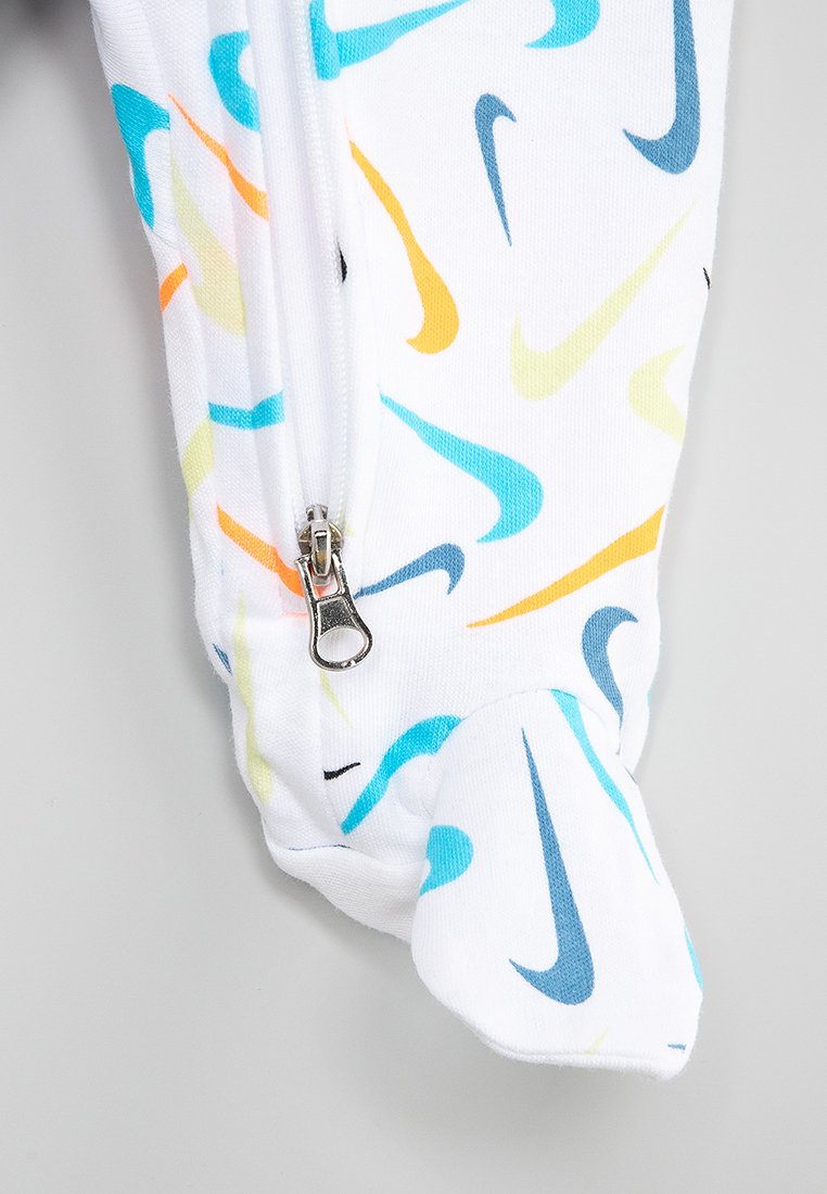 Monos con tela blanca y patrones del logo de Nike en varios colores: azul, naranja y amarillo. Presenta una cremallera en la parte delantera y mangas con puños.