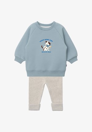 Hellblauer Pullover mit langen Ärmeln, versehen mit einem Hund und dem Text „Fetch some fun! With my pals“, kombiniert mit beigen, hochgekrempelten Hosen.