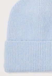 Light blue knitted woolen beanie hat with folded cuff, showing soft textured ribbed pattern.