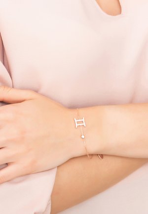 Rose gold bracelet featuring a Gemini symbol embellished with clear stones, with an adjustable chain and a small round charm.