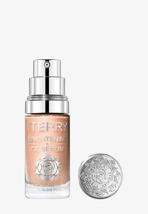 Pompflacon van By Terry Brightening CC Serum met zilverkleurige bloemmotief dop ernaast, geplaatst op een witte achtergrond.