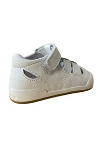 Sandalia de cuero blanca con parte trasera cerrada, correa de Velcro, recortes laterales, suela de goma y acentos texturizados.