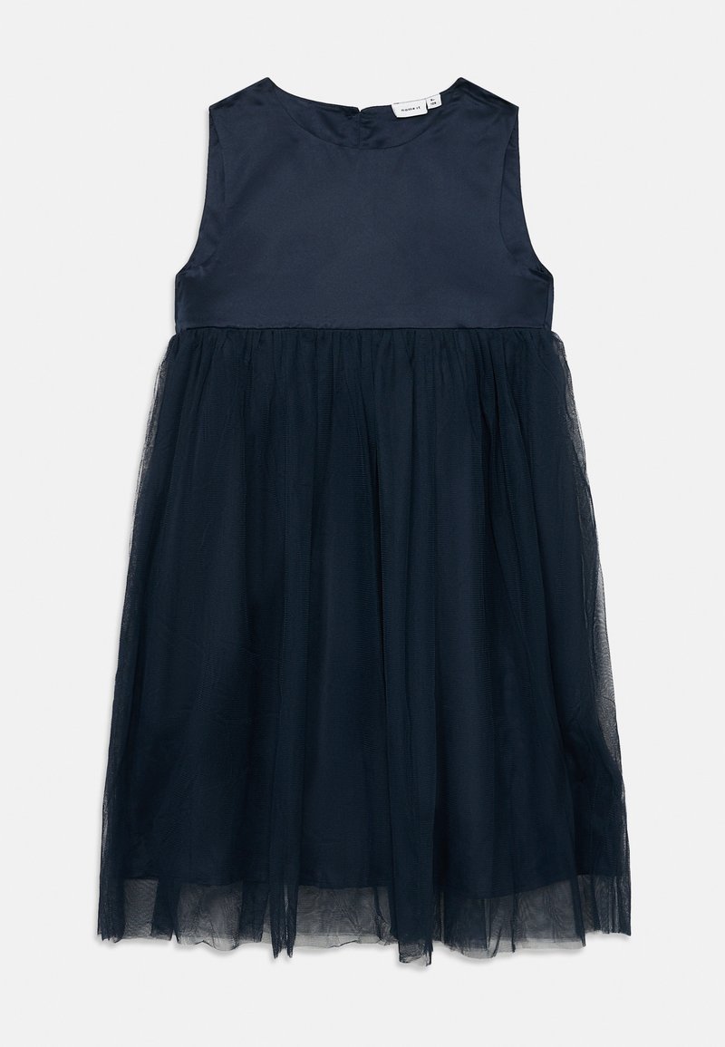 Tamsiai mėlyna be rankovių suknelė su satino liemeniu ir sluoksniuotu tiulio sijonu. Yra apvalus iškirpimas ir užsegimas užtrauktuku gale.