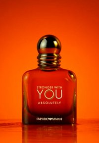 Bouteille en verre ambré avec un bouchon noir rond. Présente un texte blanc indiquant "STRONGER WITH YOU ABSOLUTELY" et "EMPORIO ARMANI" en bas.