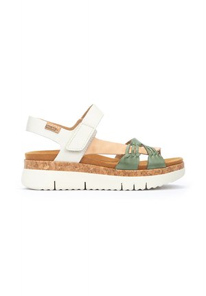 Sandales blanches avec une semelle en liège, des sangles en satin vert et une sangle de cheville réglable. Dotées d'une semelle intérieure texturée pour le confort.