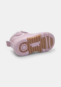 Lapse roosa tennis, külili lamamas, näidates tekstuurset põhjakihti, kus on "Bubble Gummers" logo ja šokk-absorstseeriva ringi detail.