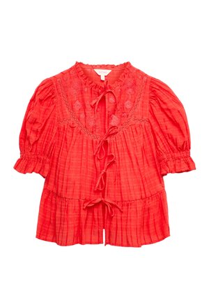 Blouse à carreaux rouges avec manches bouffantes, broderie florale, col à volants et trois fermetures à nouer à l'avant.