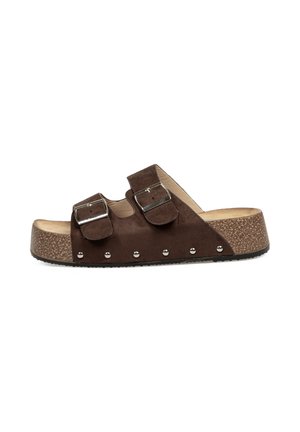 Sandalias deslizantes de ante marrón con dos correas ajustables y hebillas plateadas. Suela de plataforma de aspecto corcho con acentos de tachuelas a lo largo de la base.