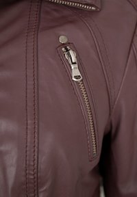 Burgunderfarbene Lederjacke mit einer Reißverschlusstasche, silbernem Zubehör, detaillierter Nahtverarbeitung und klassischem Kragendesign.