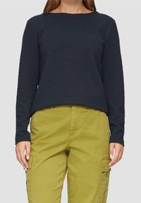 Top de manga larga texturizado en color navy con cuello redondo, combinado con pantalones cargo verde oliva que cuentan con bolsillos laterales y un ajuste recto.